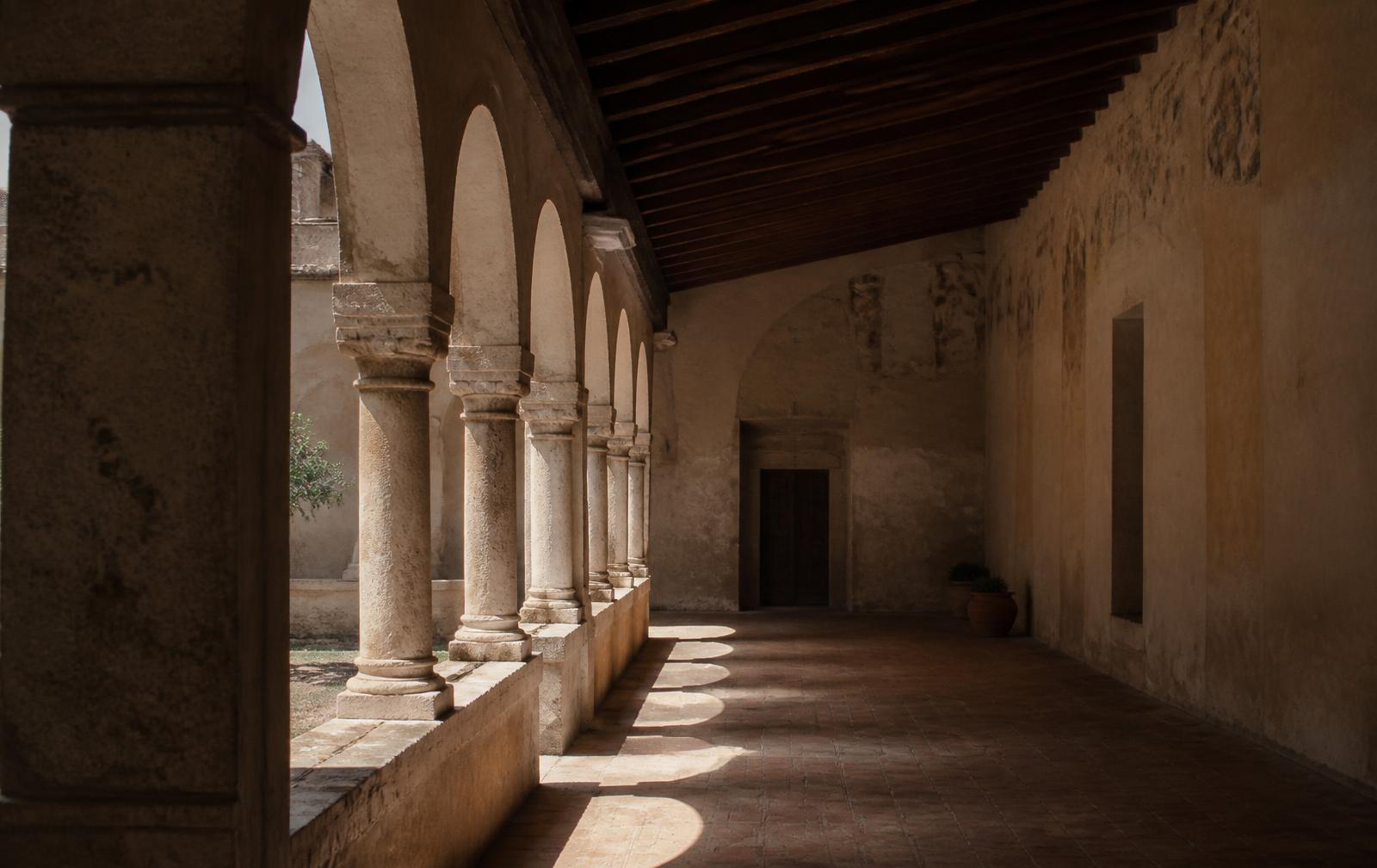 Sunlight entering an empty stone cloister.
